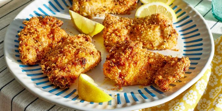 chicken cutlets with lemon wedges on a blue and white plate