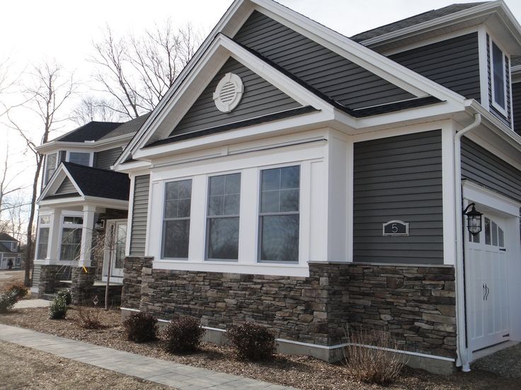 a gray house with white trim on the front and side windows is pictured in this image