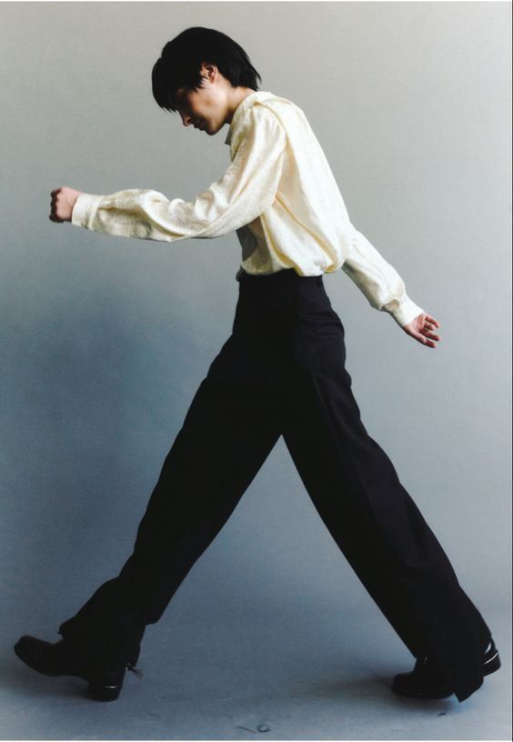 a man in black pants and a white shirt with his arms stretched out to the side