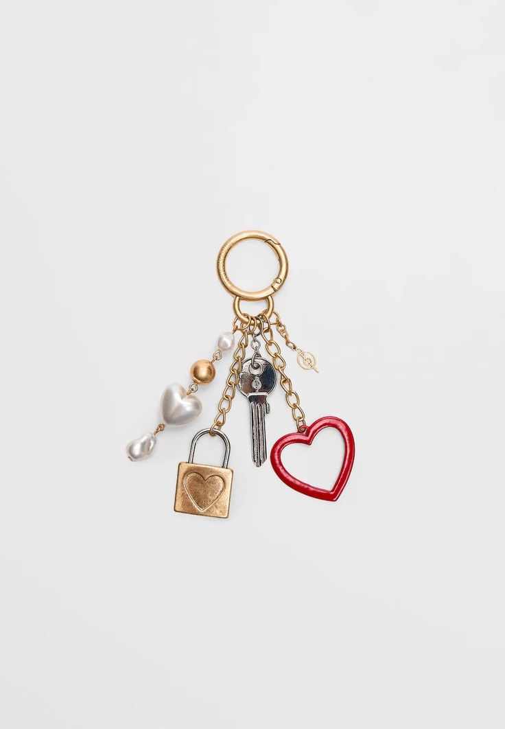 two heart shaped key chains with charms attached to them, one has a lock and the other has a chain