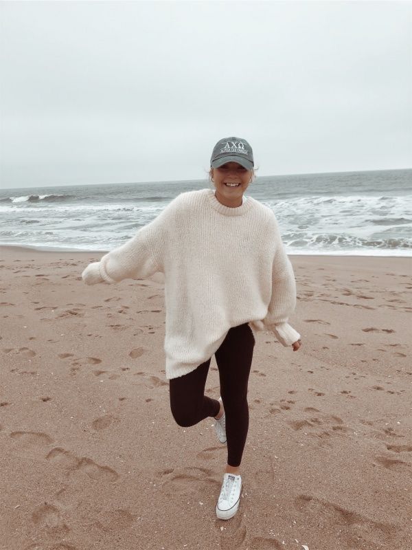 a woman is running on the beach wearing a hat