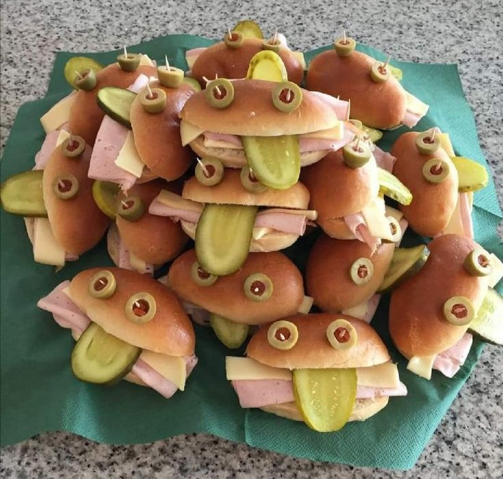 a pile of hotdogs with pickles and cheese on them sitting on top of a green napkin