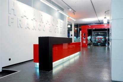 an office lobby with red and black reception desks in the center, along with white letters on the wall