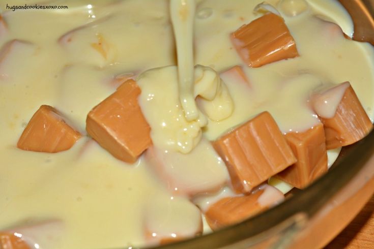 a glass bowl filled with cream and pieces of chocolate on top of a wooden table