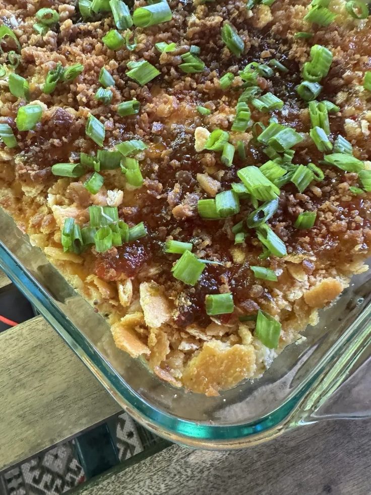 a casserole dish with meat and green onions in it sitting on a table