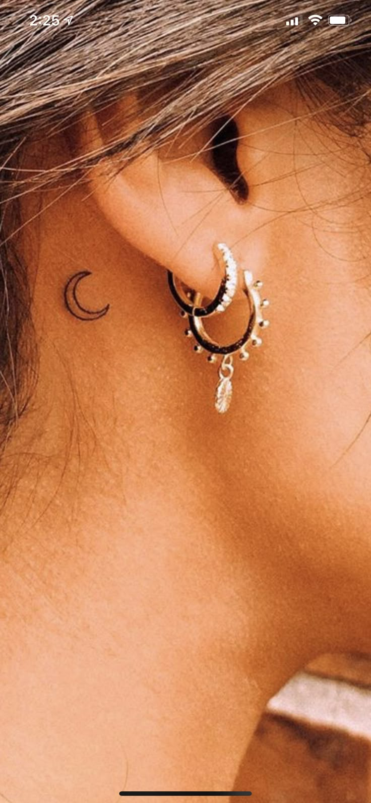 the back of a woman's ear with a crescent and star tattoo on it