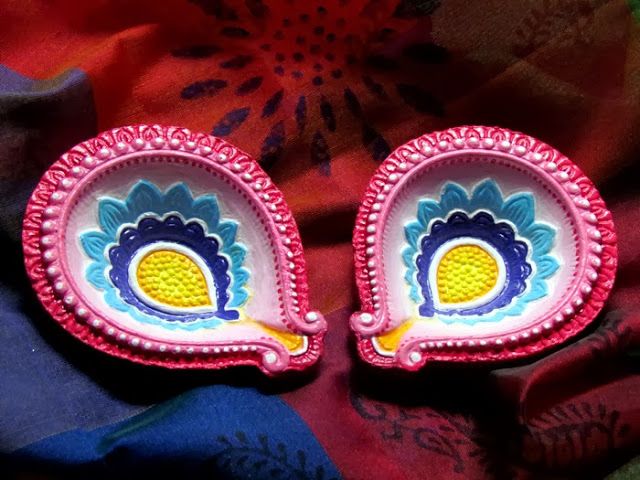 two small pink and yellow plates with designs on them sitting on a colorful cloth covered surface