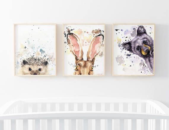 three animal prints hanging on the wall above a crib in a white nursery room