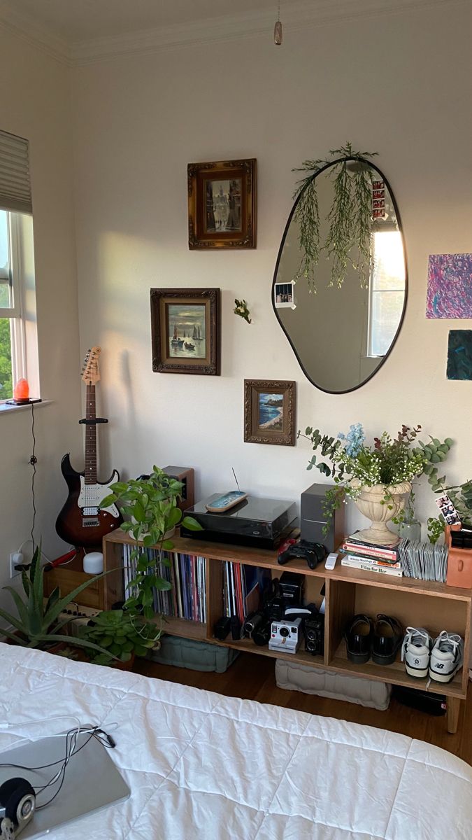 a bedroom with a bed, bookshelf and various plants