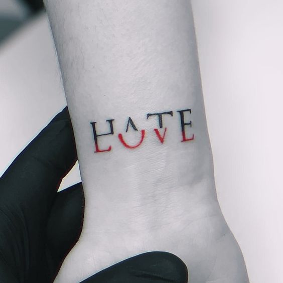 someone is holding their wrist with the word love tattooed on it's left arm