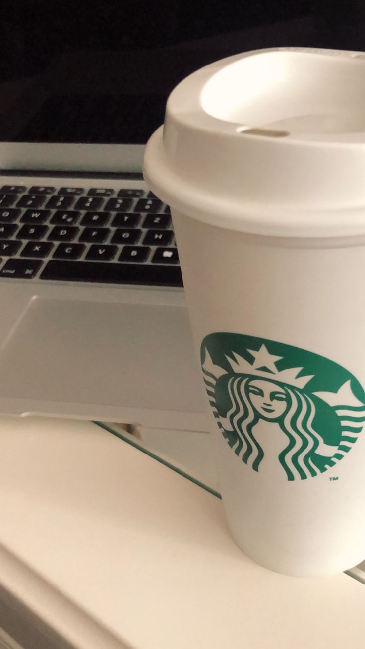 a starbucks cup sitting next to a laptop computer