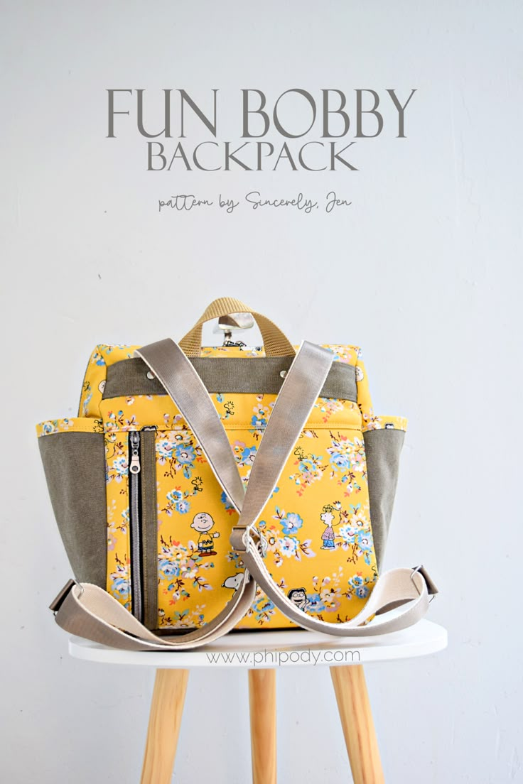 a yellow and gray purse sitting on top of a wooden stool next to a white wall