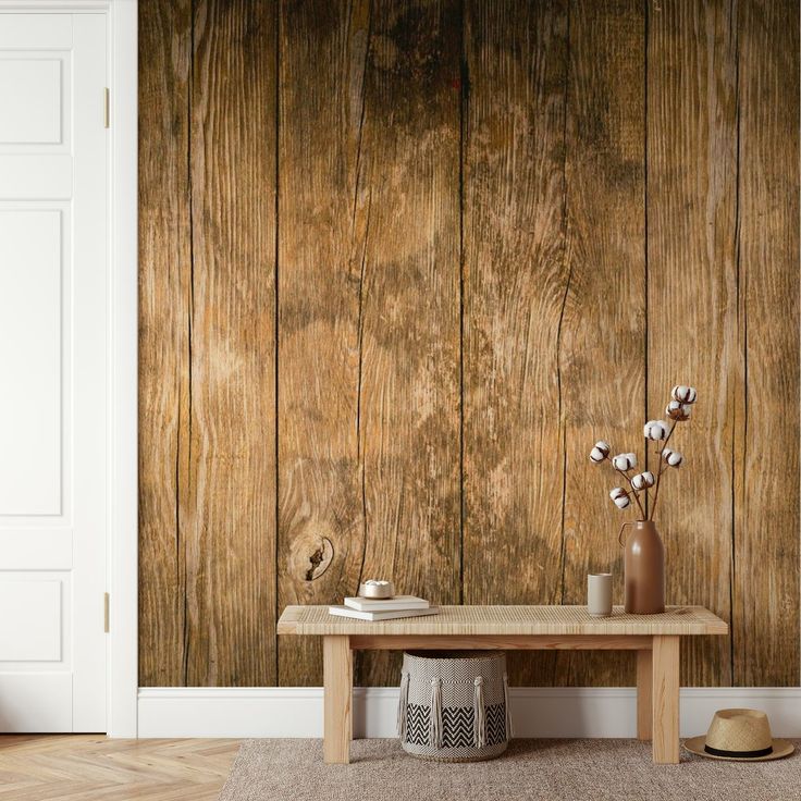 a wooden wall behind a table with vases and flowers on it in front of a white door