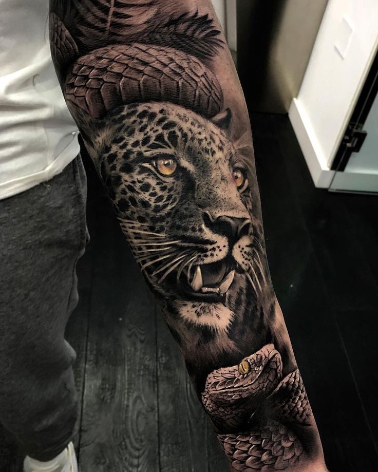 a man's arm with an animal and snake tattoo on the left side of his arm