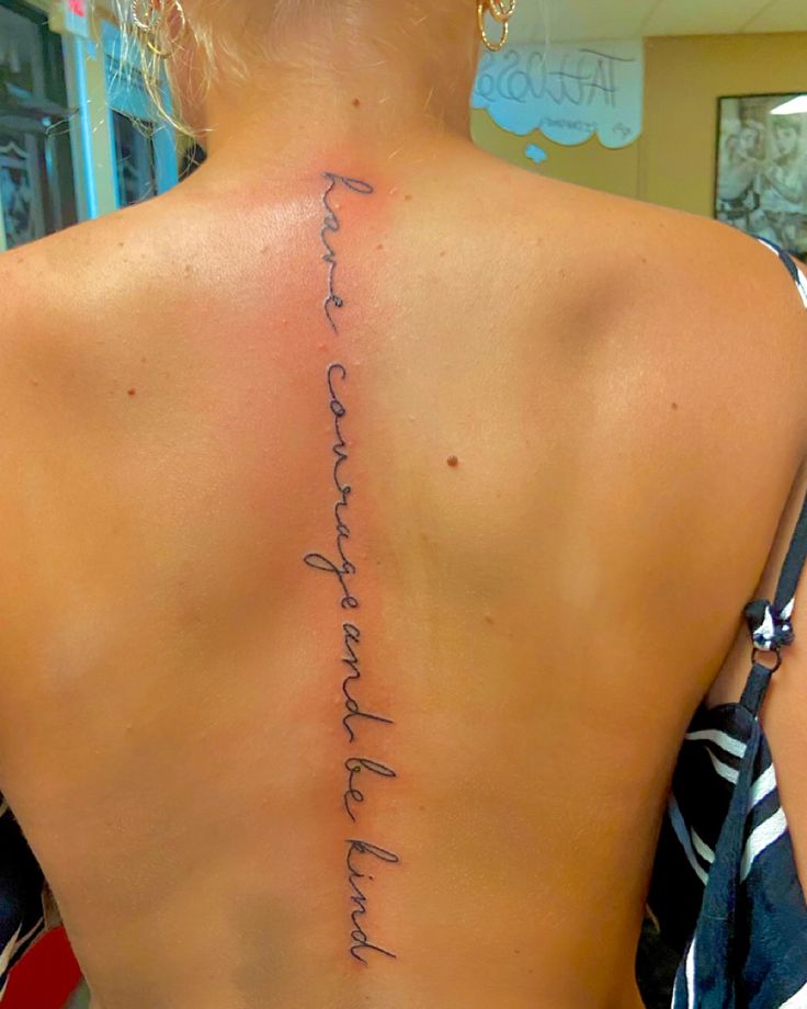 the back of a woman's neck with writing on her upper and lower back