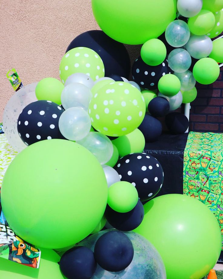 green and black balloons are hanging from the side of a building with white polka dots on them