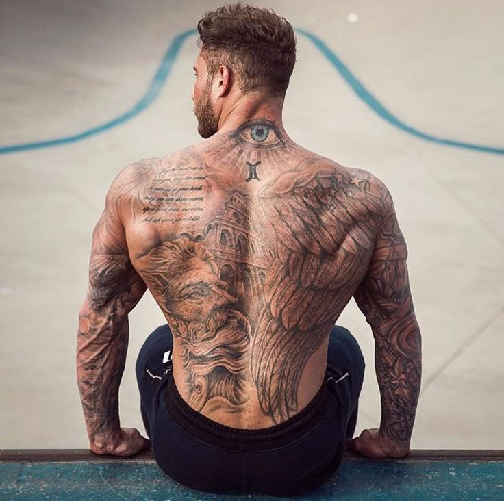 a man sitting on the ground with his back turned to the camera and tattoos all over his body