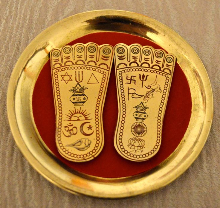 two golden footprints on a red plate with gold trimmings and symbols painted on them