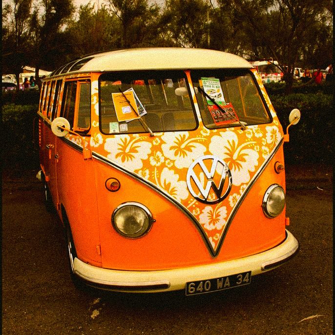 an orange and white vw bus parked in a parking lot