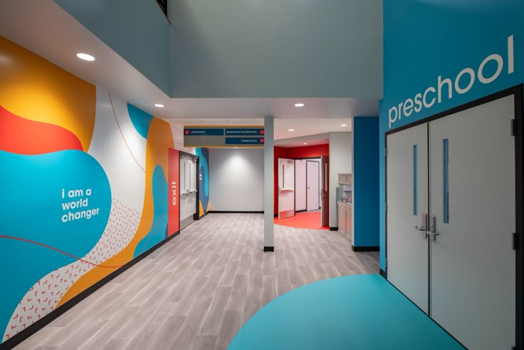 an empty school hallway with colorful painted walls and doors on either side of the room