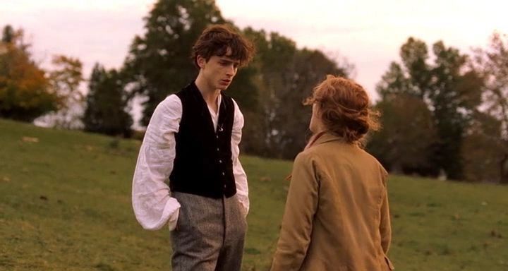 two young men standing on top of a lush green field