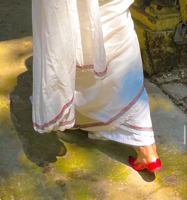 a woman in white is walking down the street with her red shoes and dress on