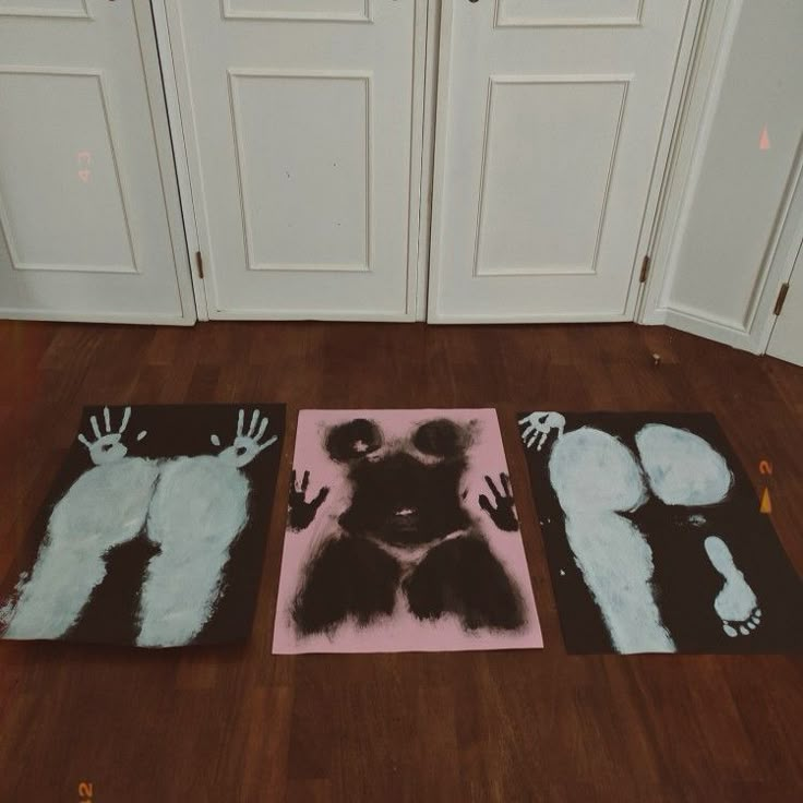 three pieces of artwork on the ground in front of two doors and one with hands