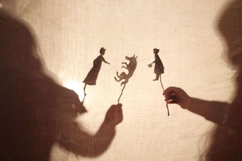 the shadow of two people holding flowers in front of a white sheet with cats on it