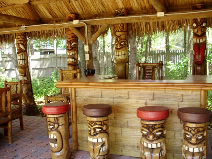 an outdoor bar with tiki heads on the top and stools at the bottom