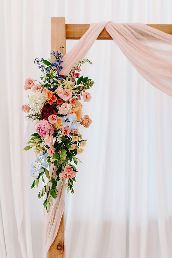 a wooden cross decorated with flowers and greenery for a wedding ceremony or special event