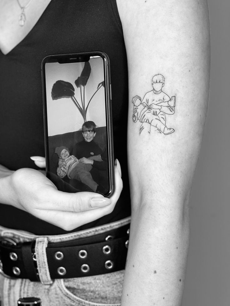 a person holding a cell phone with a tattoo on their arm