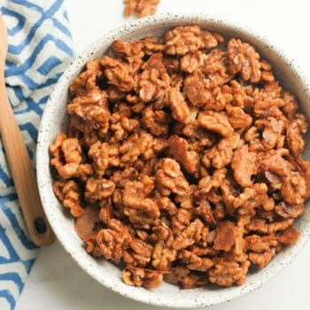 a bowl filled with granola sitting on top of a blue and white towel next to a wooden spoon