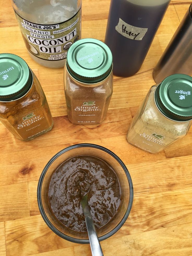 there are many jars on the table with some liquid in them and a spoon next to it