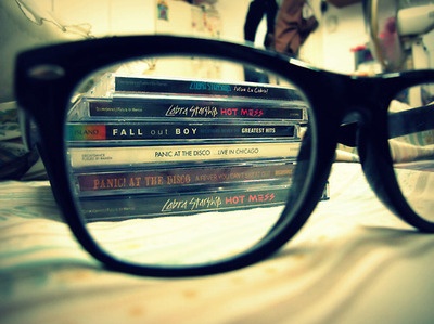 a stack of books sitting on top of a bed under a pair of glasses