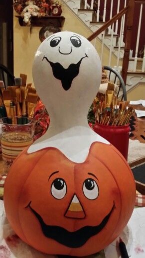 a halloween pumpkin with a ghost face on it's head sitting on top of a table