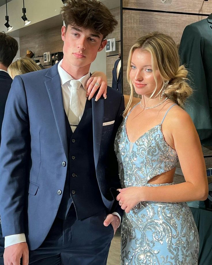 a man in a blue suit standing next to a woman wearing a light blue dress