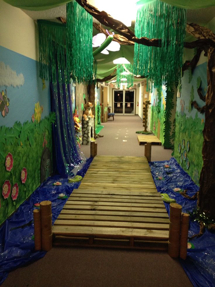 an indoor play area with blue tarps and green curtains on the walls, along with a wooden walkway