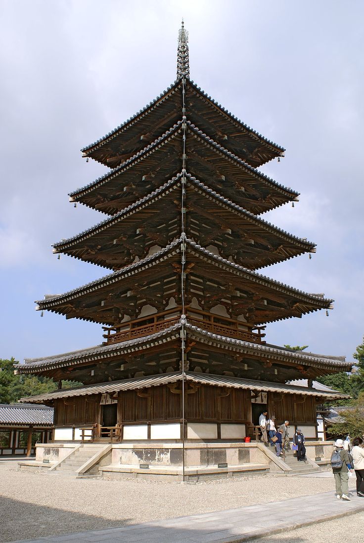 a tall wooden structure sitting in the middle of a park with people standing around it