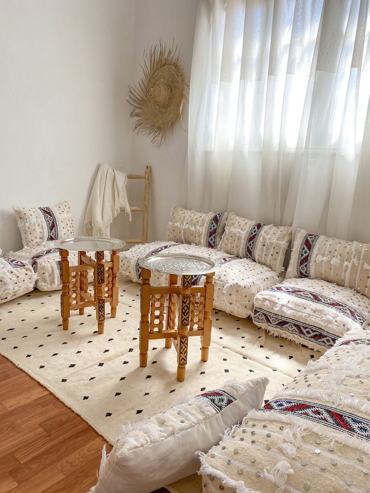 a living room filled with lots of furniture and pillows on top of a wooden floor