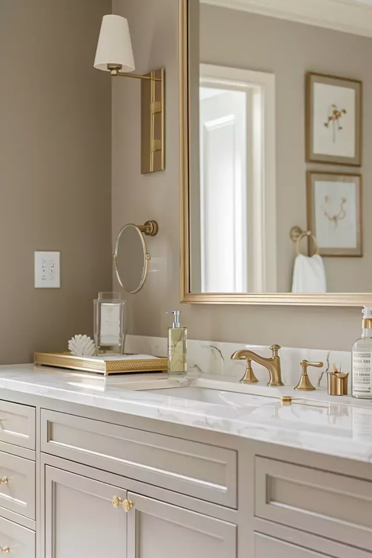 a bathroom vanity with two sinks and a large mirror above it, all in gold