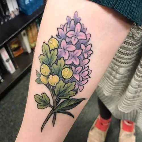 a woman's leg with a flower tattoo on her left arm and purple flowers in the center