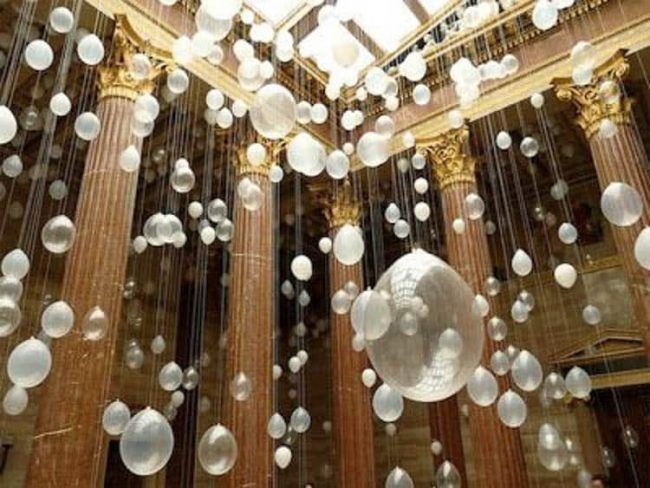 the ceiling is decorated with white balls and chandeliers hanging from it's sides