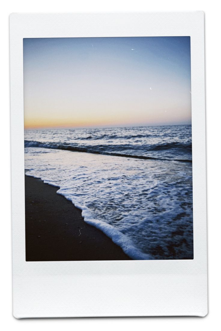 a polaroid photo of the ocean at sunset with waves coming in from the shore