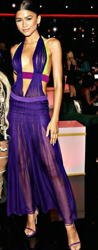 a woman in a purple dress posing for the camera