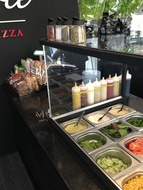 a buffet with salads and condiments on the counter in front of it