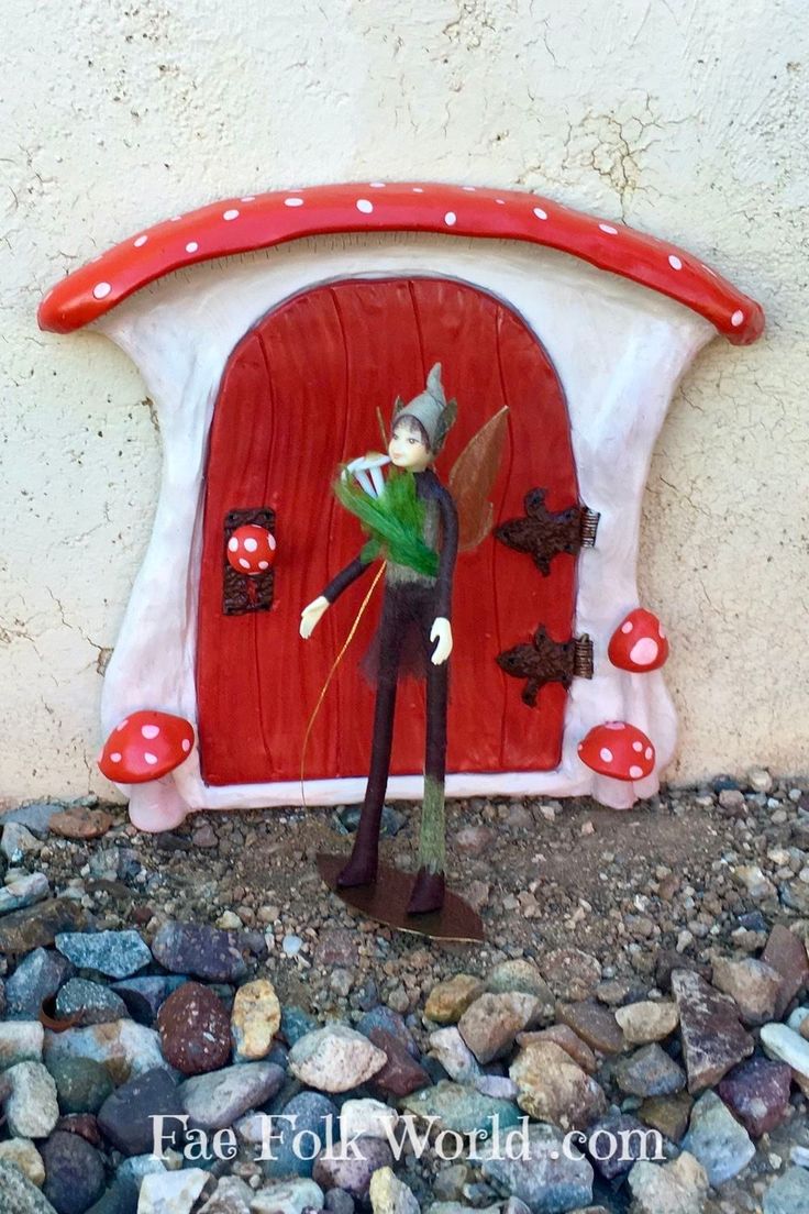 a red and white door with a gnome figurine next to it on some rocks