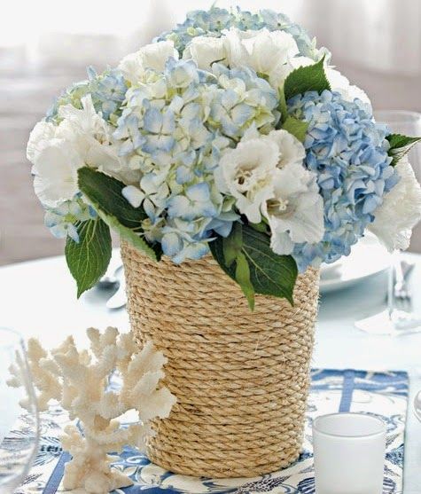 there is a basket with blue and white flowers in it sitting on the dining room table