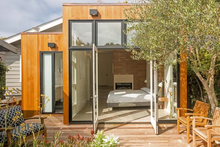 a bedroom with wooden walls and flooring next to a bed in the middle of a garden