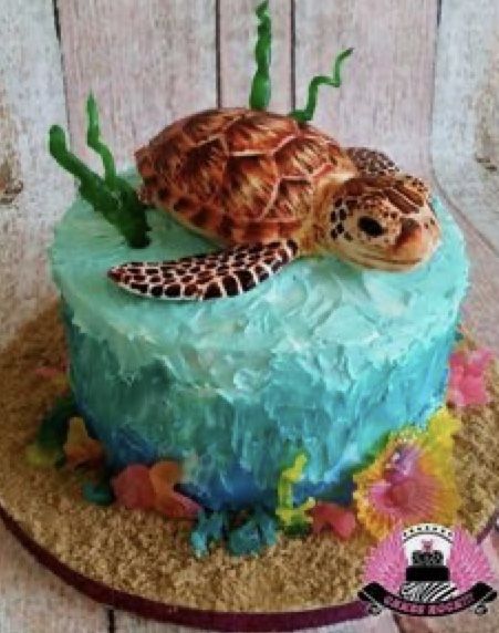 there is a cake that looks like a sea turtle on the beach with corals