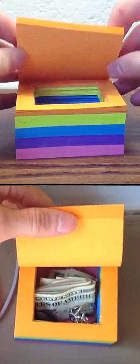 a person holding a small toy boat in a box that is made out of colored paper